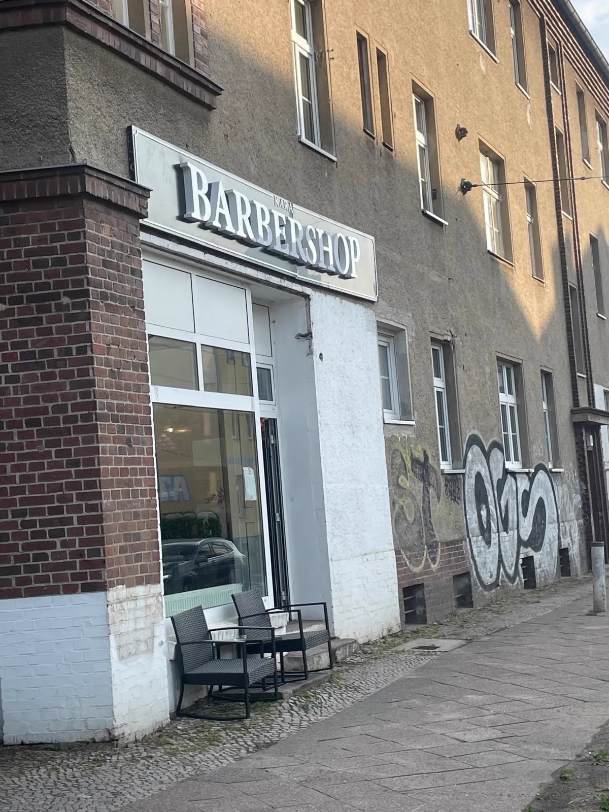 Entrance of Kara Barbershop with black shop sign