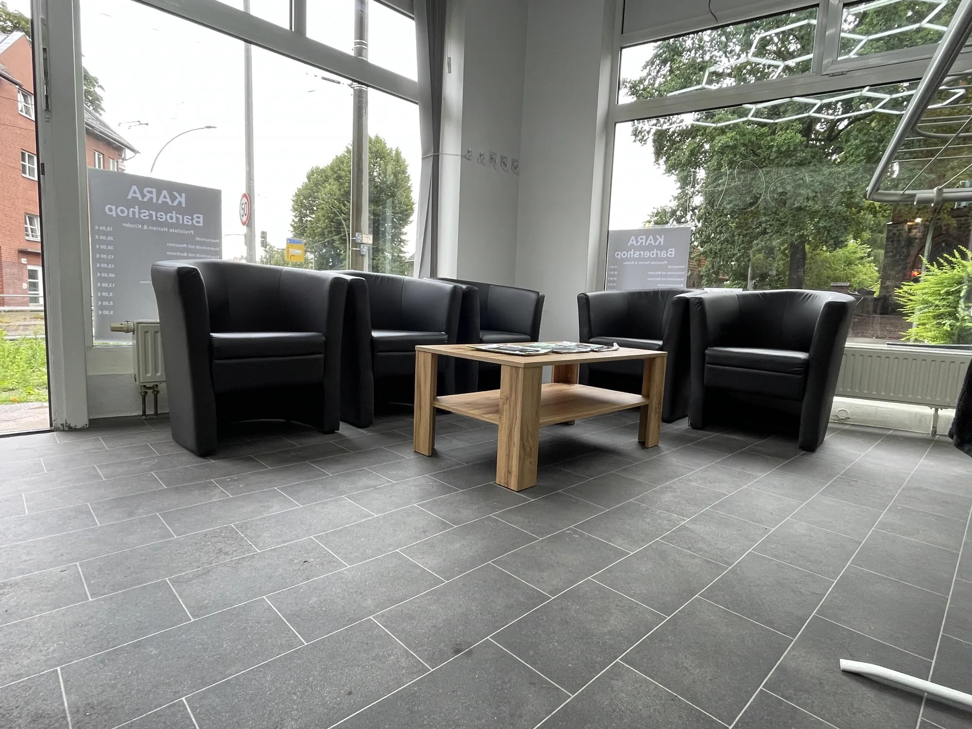 Wartebereich mit schwarzen Ledersesseln im Kara Barbershop